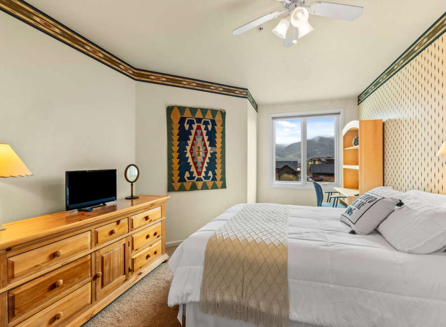This cozy bedroom features a comfortable bed with a stylish throw blanket and decorative pillows.