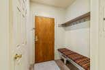 Step into this inviting entryway, featuring a warm wooden door and a convenient bench with striped cushions.