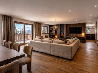 Experience luxury mountain living in this stunning chalet, featuring a spacious open-plan living area with a cozy fireplace and breathtaking panoramic views of snow-capped peaks.