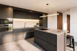 Experience modern luxury in this stunning kitchen, featuring sleek dark wood cabinetry and a spacious island with a built-in cooktop.