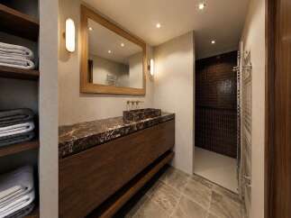 Experience luxury in this modern bathroom featuring a stunning marble vanity with a vessel sink and warm wood cabinetry.