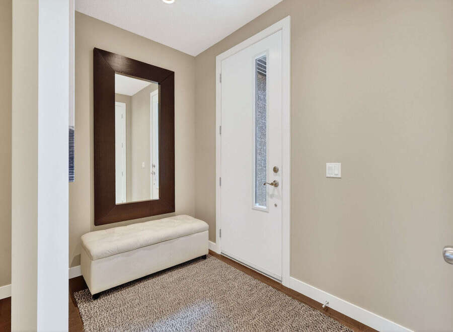 Step into this inviting entryway, showcasing a stylish mirror and a comfortable bench, perfect for a welcoming first impression.