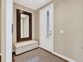 Step into this inviting entryway, showcasing a stylish mirror and a comfortable bench, perfect for a welcoming first impression.