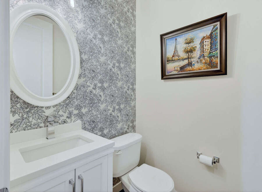 This elegant bathroom features a stylish oval mirror above a pristine white vanity.