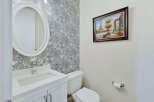 This elegant bathroom features a stylish oval mirror above a pristine white vanity.
