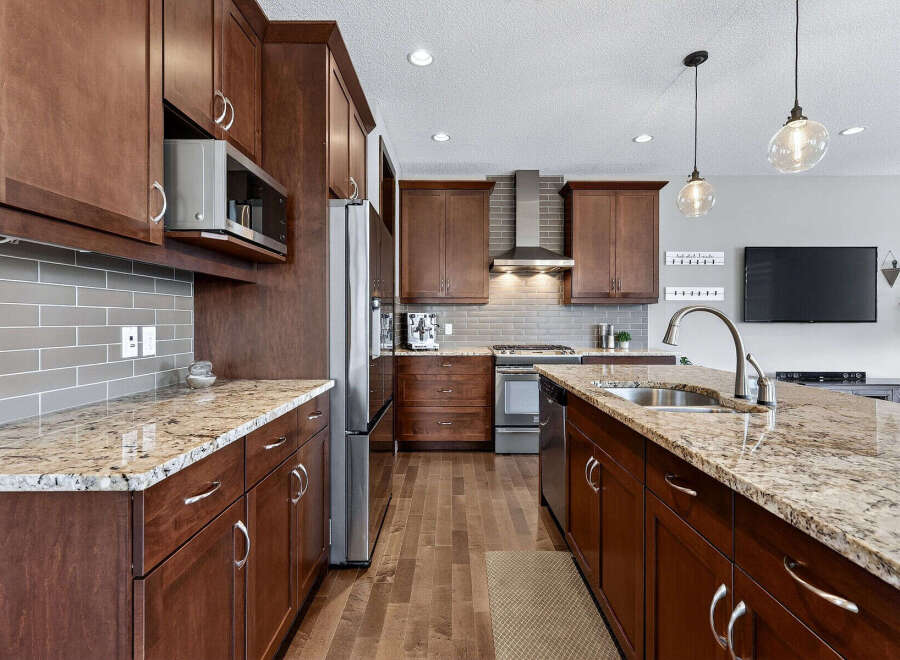 This stunning kitchen boasts rich, dark wood cabinetry and elegant granite countertops, creating a warm and inviting atmosphere.