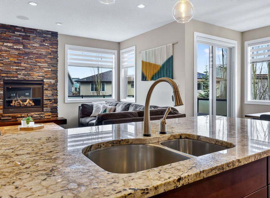 This stunning kitchen boasts a beautiful granite countertop and a modern stainless steel sink, perfect for culinary enthusiasts.