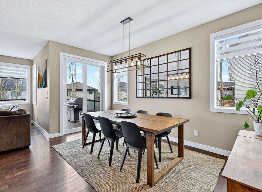 This stunning dining room features a modern aesthetic with a beautiful wooden dining table and stylish black chairs.