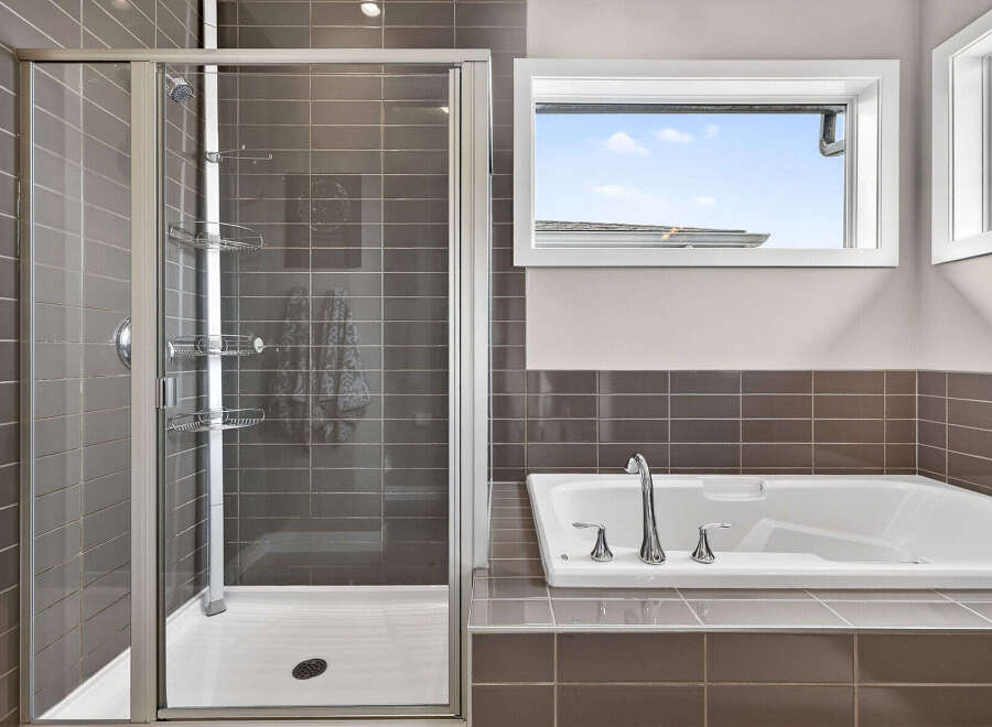 Step into luxury with this stunning bathroom featuring a sleek glass shower and a relaxing bathtub.