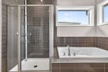 Step into luxury with this stunning bathroom featuring a sleek glass shower and a relaxing bathtub.