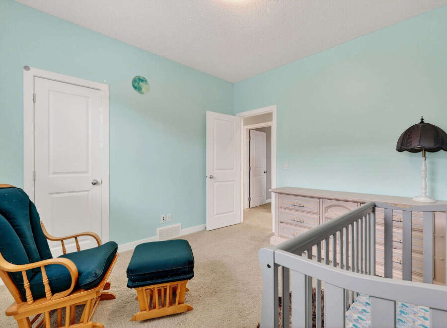 This charming nursery features a serene atmosphere with its light blue walls and a cozy rocking chair.
