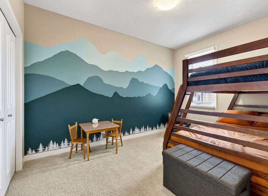 This charming bedroom features a unique mountain-themed mural, creating a serene and playful atmosphere.