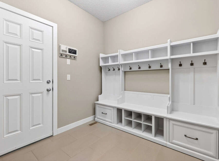 This entryway boasts a custom-built white storage unit, perfect for organizing coats, shoes, and accessories.