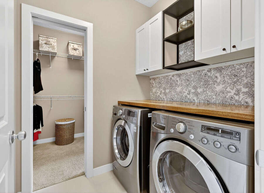 Step into this beautifully designed laundry room, featuring modern appliances and ample storage.