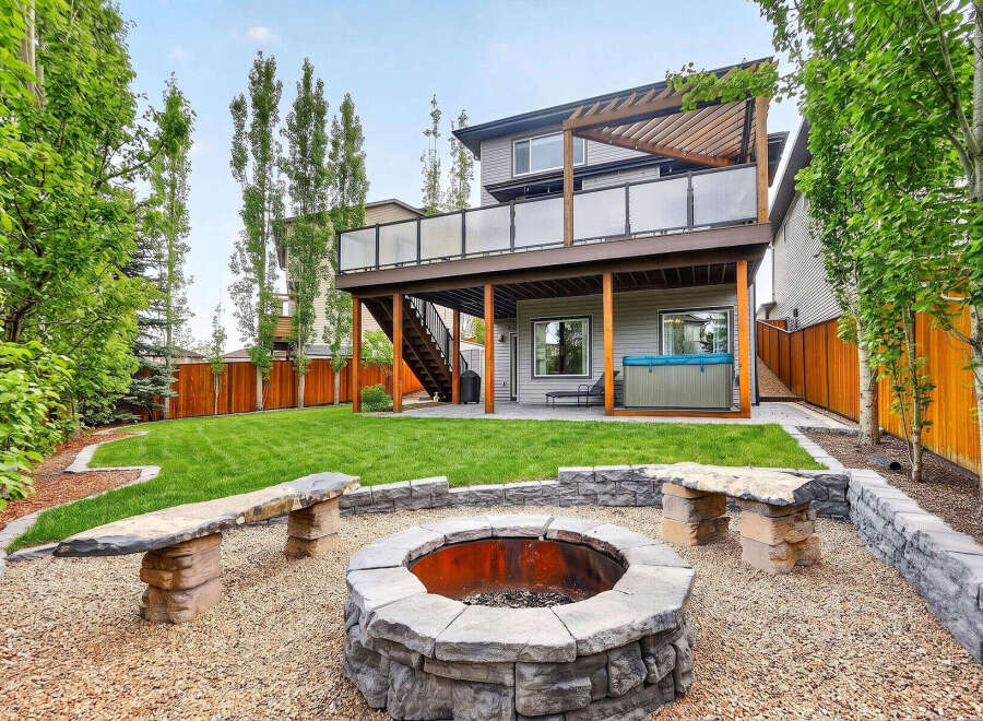 Enjoy outdoor living at its finest in this stunning backyard oasis! Featuring a spacious deck, a cozy fire pit area, and lush green lawn, this property is perfect for entertaining or relaxing.