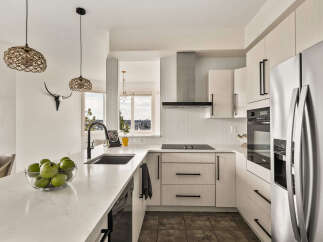 This modern kitchen boasts sleek, white cabinetry and a stunning quartz countertop, creating a bright and inviting space.