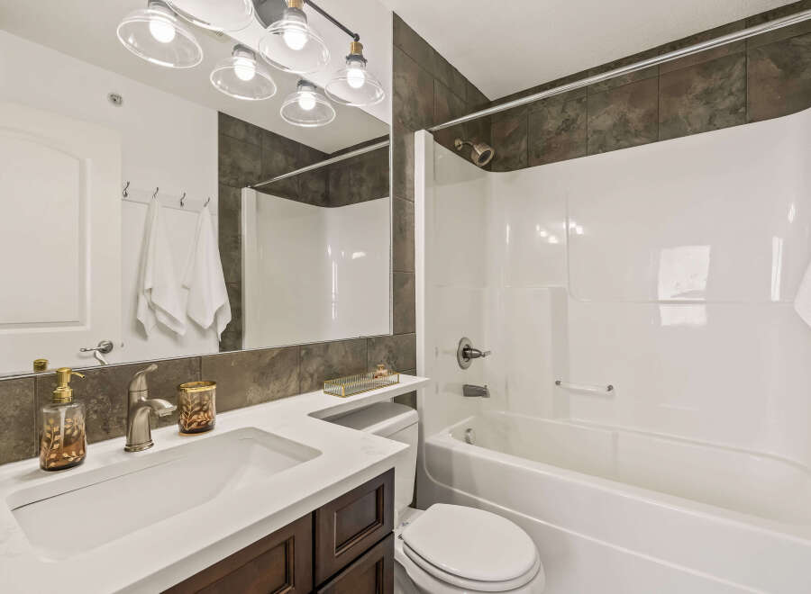 This modern bathroom features a sleek white vanity with a matching sink and dark wood cabinetry.