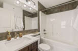 This modern bathroom features a sleek white vanity with a matching sink and dark wood cabinetry.