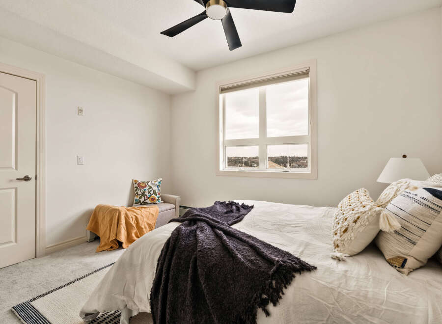 This cozy bedroom offers a serene retreat with its neutral color palette and ample natural light.
