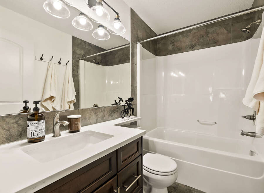 This modern bathroom features a sleek white countertop and dark wood cabinetry, creating a stylish and functional space.