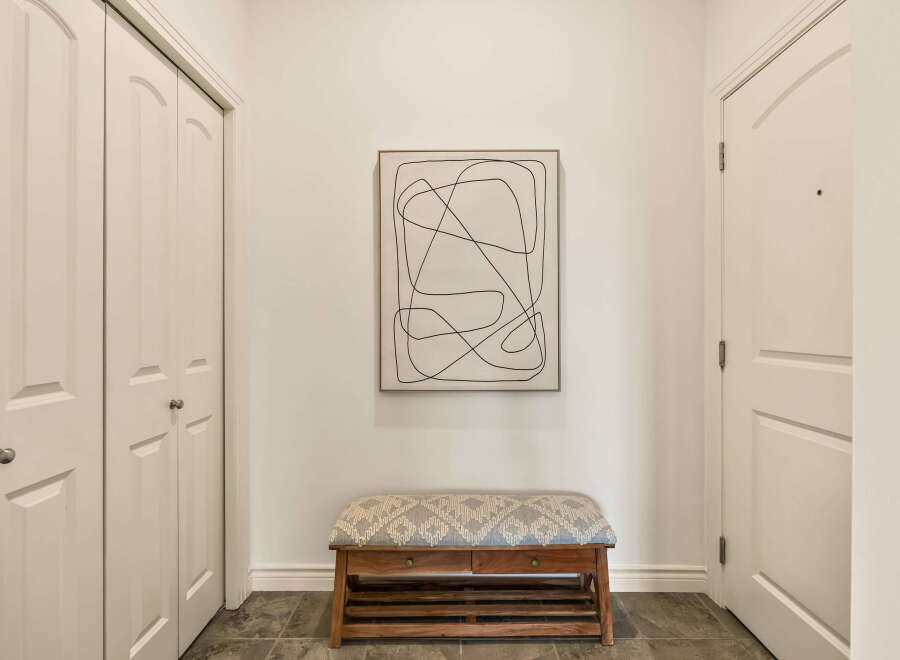 Step into this inviting entryway, showcasing a stylish bench and a captivating piece of art.