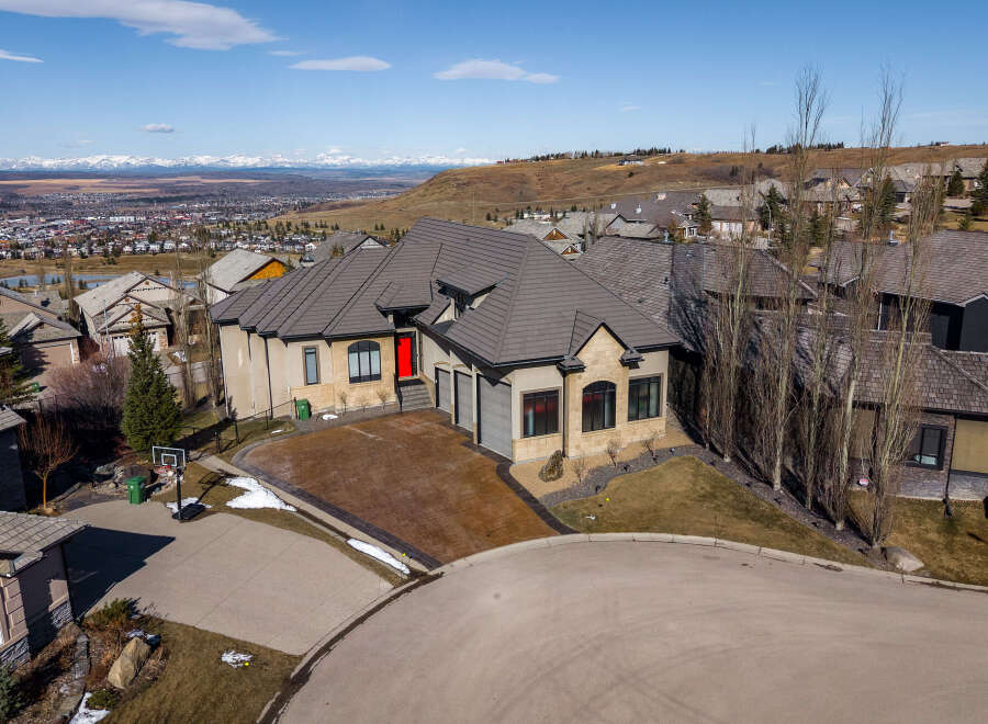 This stunning property boasts a modern design with a striking red front door, complemented by a beautifully paved driveway.