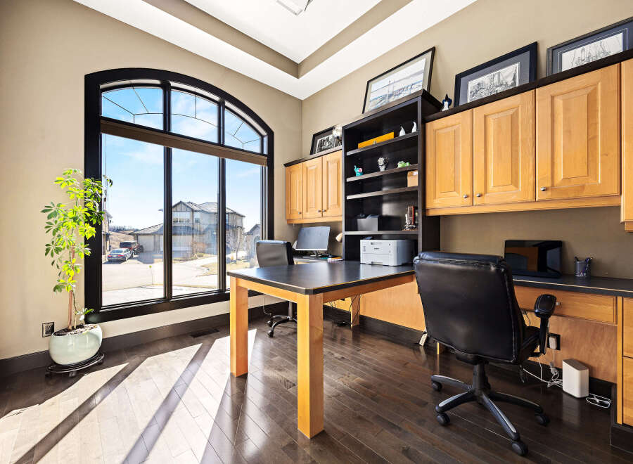 This stunning home office boasts an abundance of natural light, thanks to its expansive arched window.