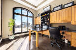 This stunning home office boasts an abundance of natural light, thanks to its expansive arched window.