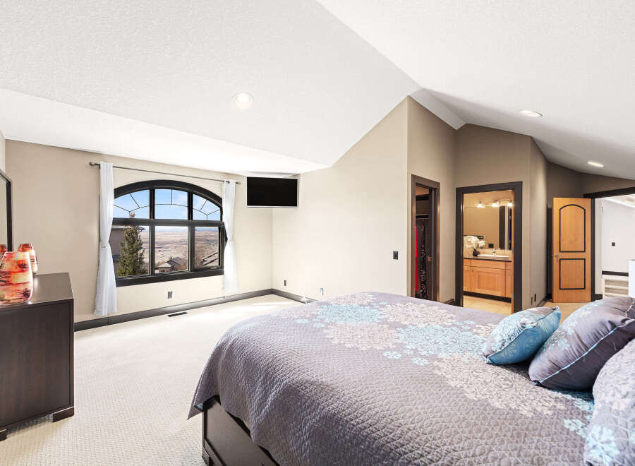 This stunning bedroom boasts a serene ambiance with its neutral color palette and ample natural light.
