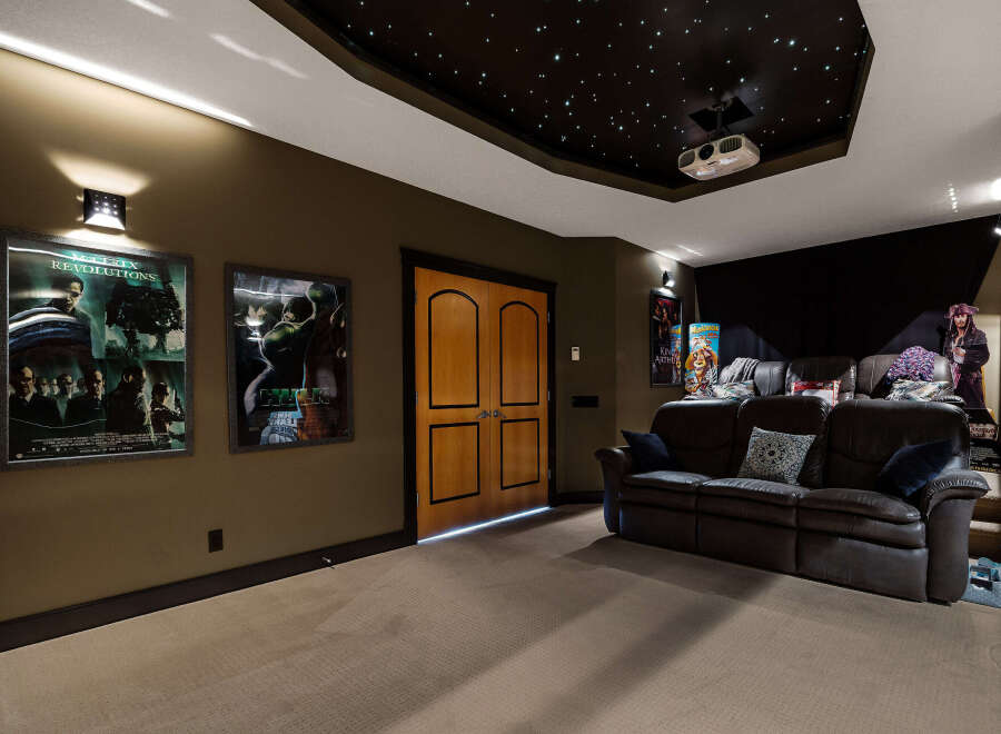Step into luxury with this stunning home theater! Featuring a star-lit ceiling, comfortable seating, and movie posters, this space is perfect for movie nights.