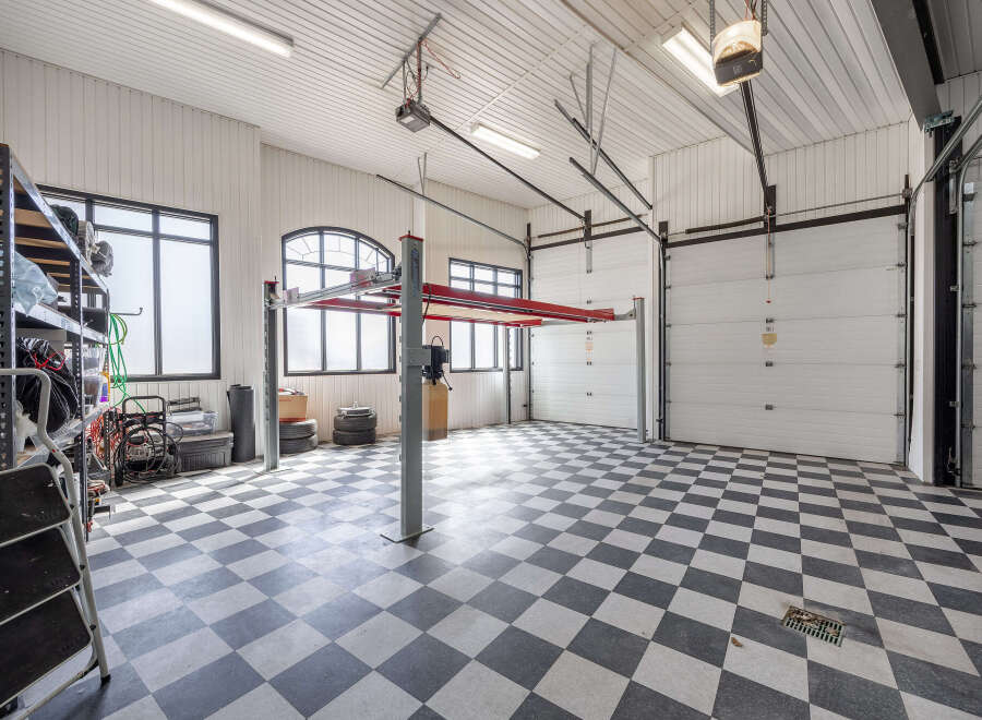 This spacious garage features a two-post car lift, perfect for automotive enthusiasts or professionals.