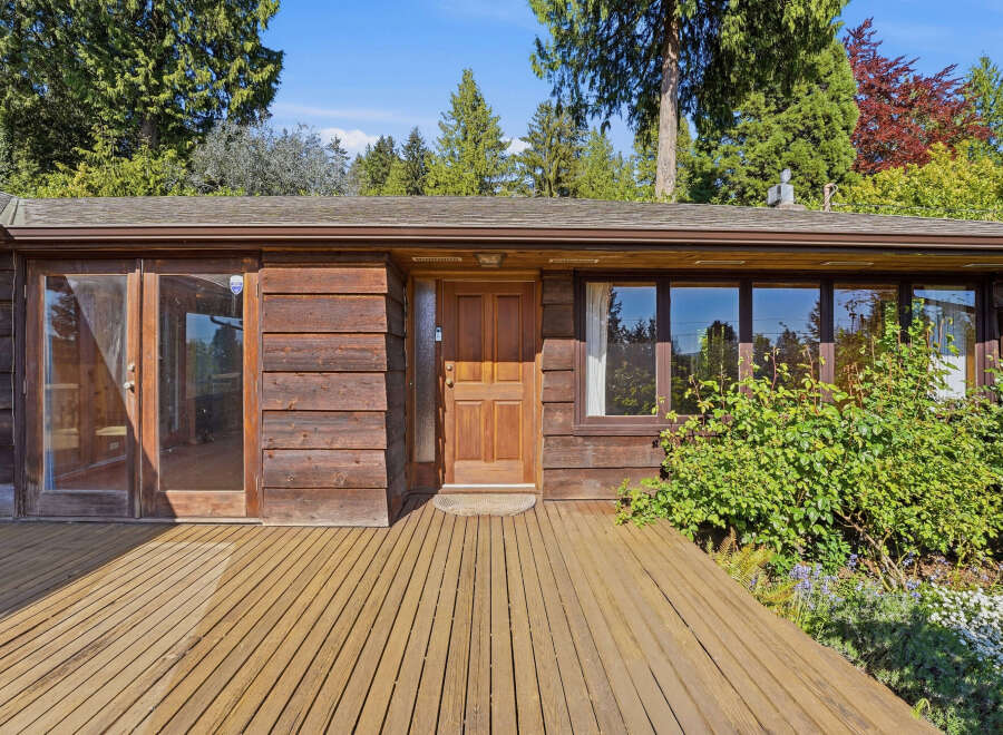 This stunning property boasts a warm and inviting exterior with its natural wood siding and a welcoming wooden deck.