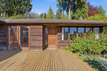 This stunning property boasts a warm and inviting exterior with its natural wood siding and a welcoming wooden deck.