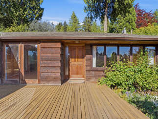 This stunning property boasts a warm and inviting exterior with its natural wood siding and a welcoming wooden deck.