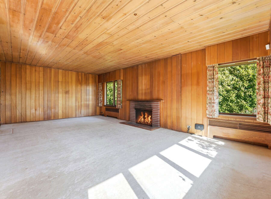 Step into this inviting living space featuring warm wood paneling and a cozy fireplace, perfect for relaxing evenings.