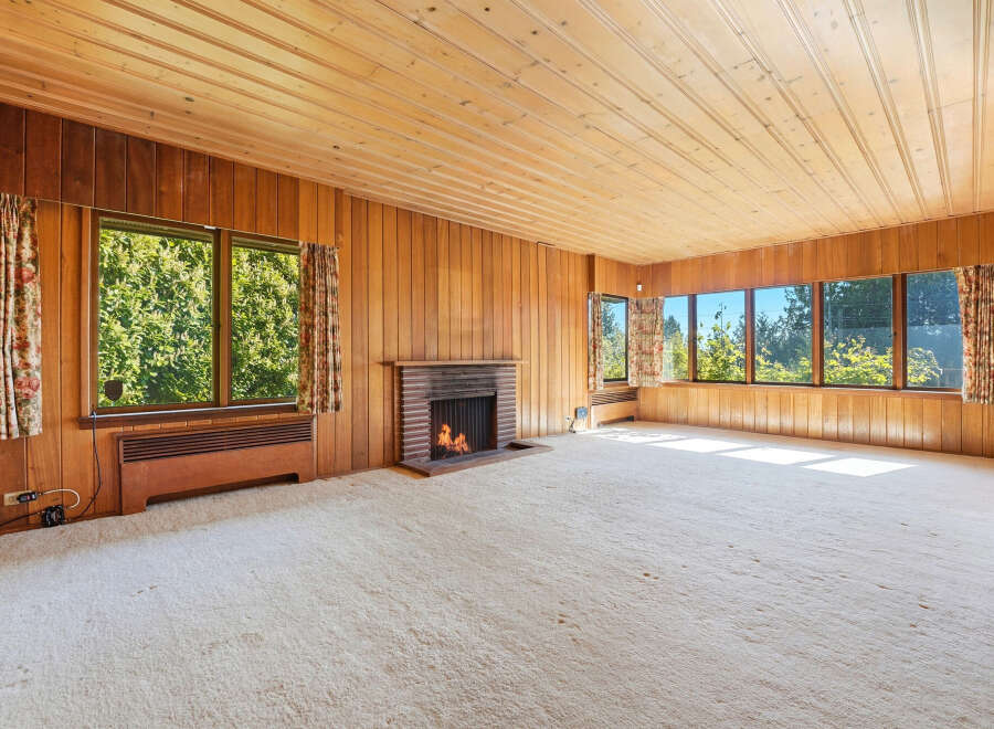 Step into this inviting living space, featuring warm wood paneling and a cozy fireplace.