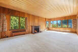 Step into this inviting living space, featuring warm wood paneling and a cozy fireplace.