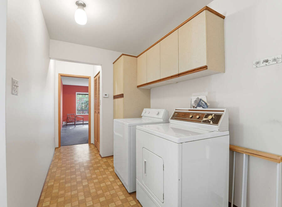 Step into this inviting laundry room, complete with a washer and dryer, and ample storage cabinets.