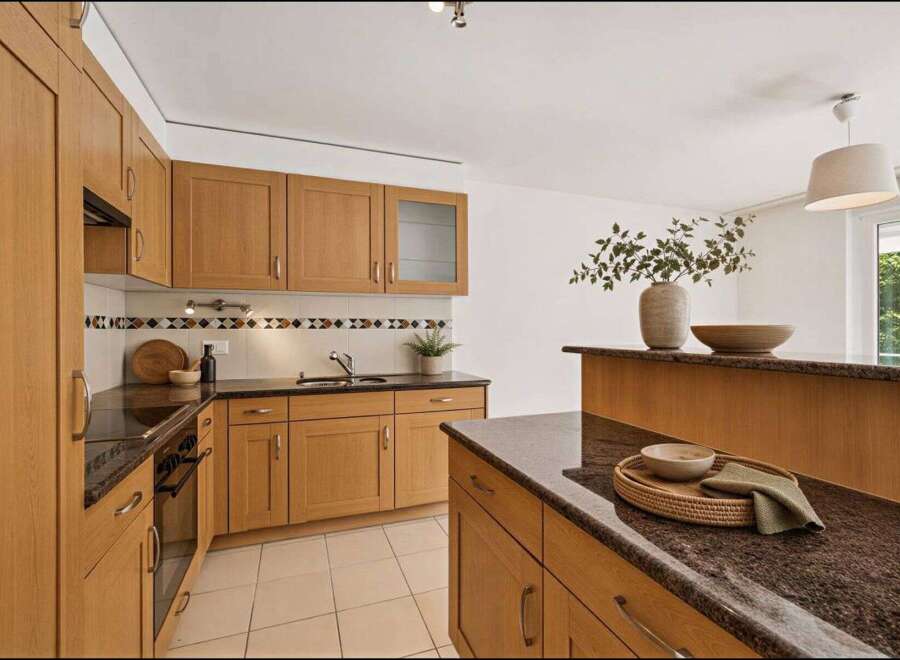 This stunning kitchen boasts beautiful wooden cabinetry and sleek granite countertops, creating a warm and inviting atmosphere.