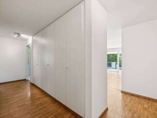 This bright and airy hallway features beautiful hardwood floors and a series of built-in white cabinets, offering ample storage space.
