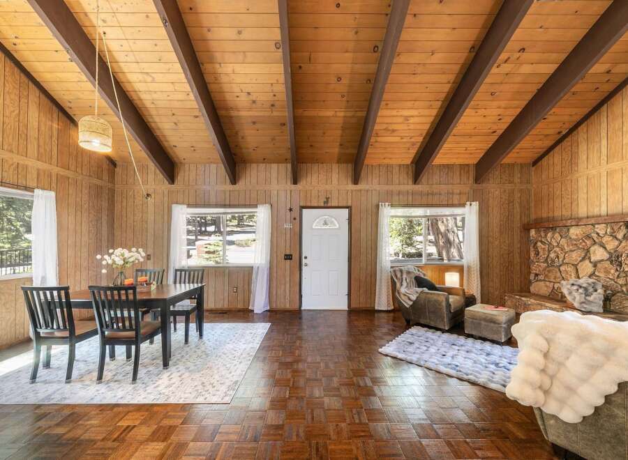 Step into this charming cabin retreat, featuring a cozy living space with a stone fireplace and warm wood paneling.
