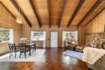 Step into this charming cabin retreat, featuring a cozy living space with a stone fireplace and warm wood paneling.