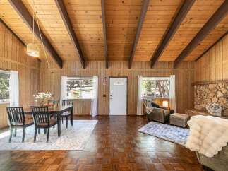 Step into this charming cabin retreat, featuring a cozy living space with a stone fireplace and warm wood paneling.