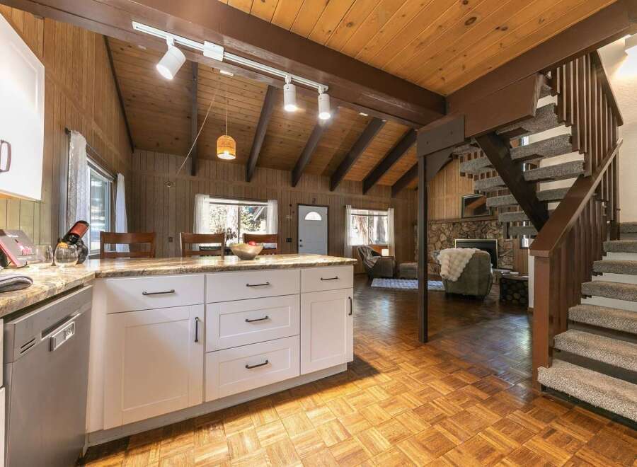 Step into this charming cabin-style home, featuring a cozy living space with a fireplace and a well-equipped kitchen.