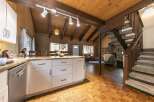 Step into this charming cabin-style home, featuring a cozy living space with a fireplace and a well-equipped kitchen.