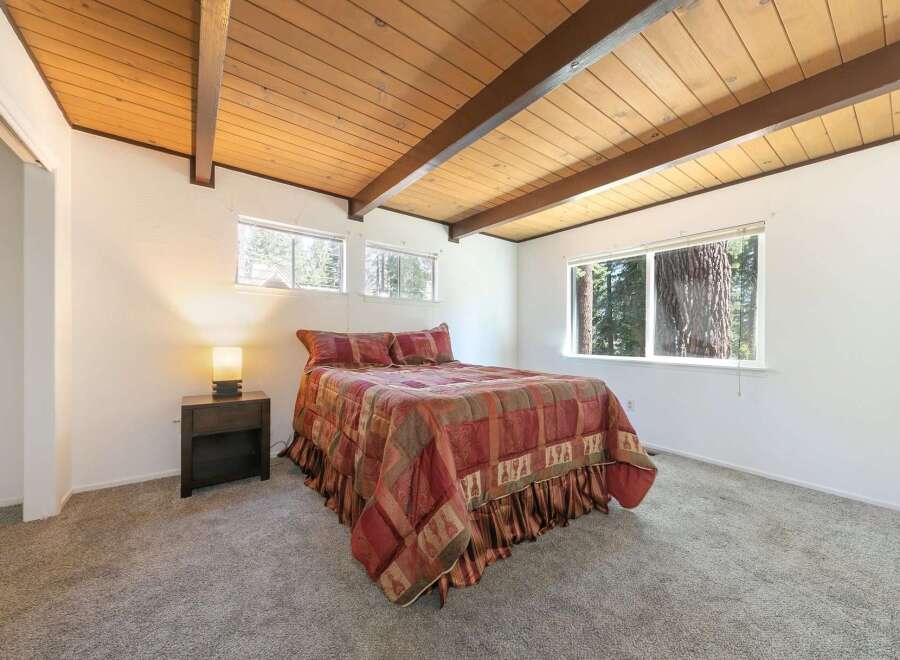 This cozy bedroom features a warm, inviting atmosphere with its wooden ceiling and ample natural light.