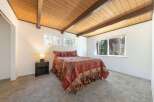 This cozy bedroom features a warm, inviting atmosphere with its wooden ceiling and ample natural light.