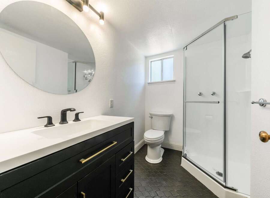 Step into a beautifully designed bathroom featuring a sleek black vanity with gold hardware, offering both style and functionality.