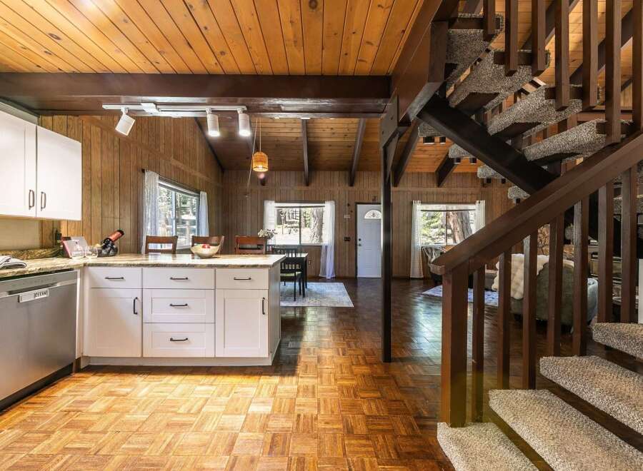 Step into this charming cabin-style home, featuring a warm and inviting interior with wood paneling and a cozy atmosphere.
