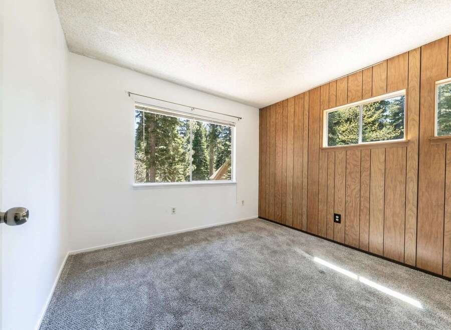 This inviting room features a cozy carpet and a large window that offers stunning views of the surrounding trees.